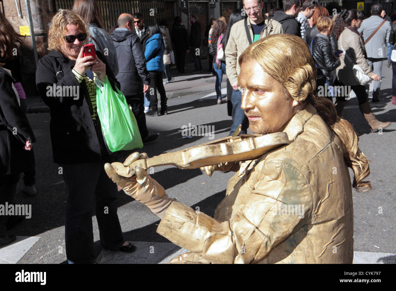 Gold painted man living statue street entertainer, classical musician posing with violin, Madrid, Spain Stock Photo