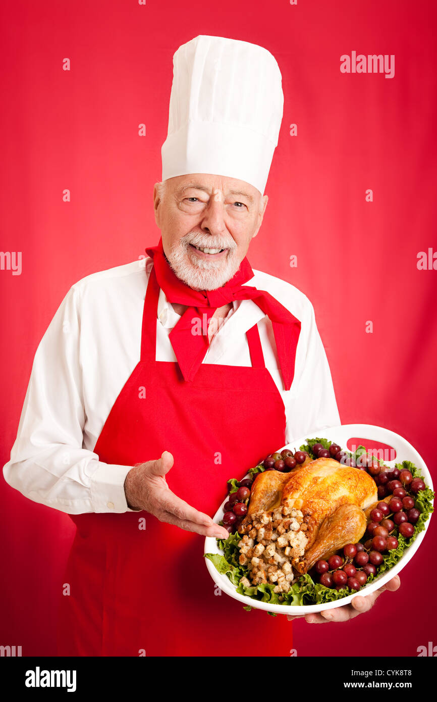 Handsome, experienced chef holding stuffed turkey dinner. Red