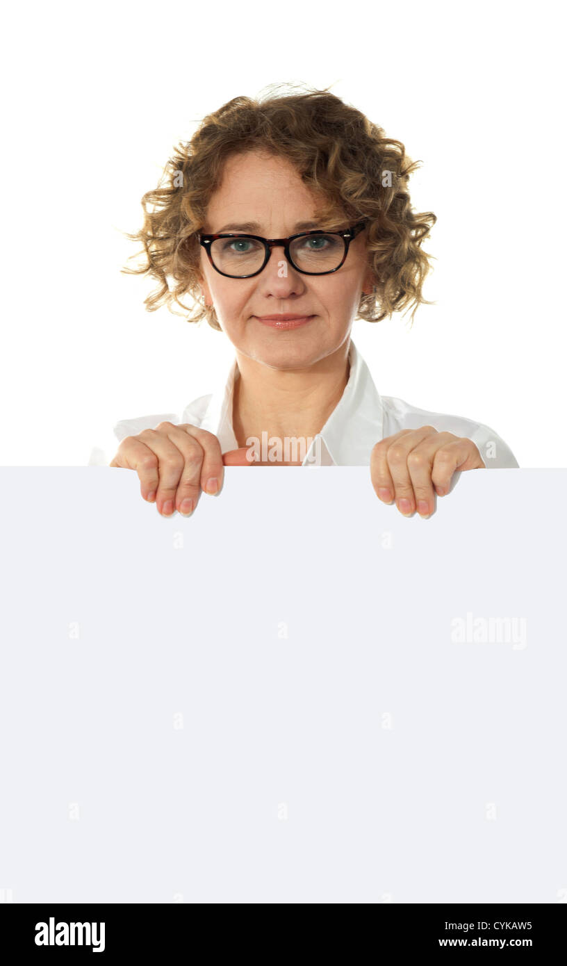 Aged woman behind big blank white banner ad looking right into camera Stock Photo