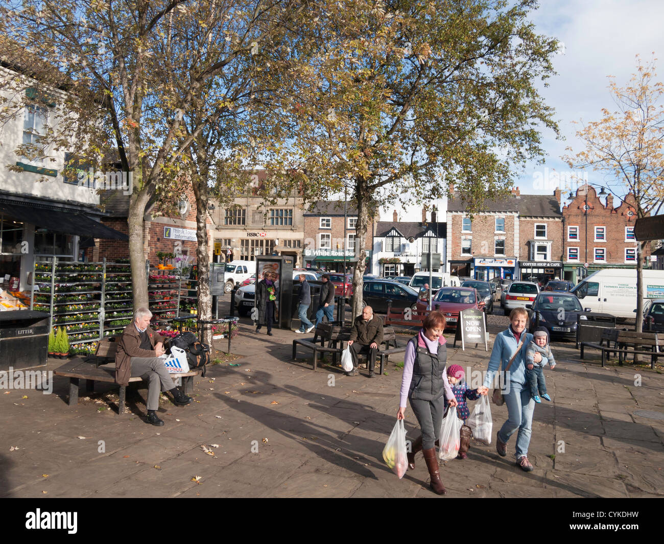 The Market Place in Thirsk town centre North Yorkshire UK on a sunny autumn day with family carrying shopping Stock Photo