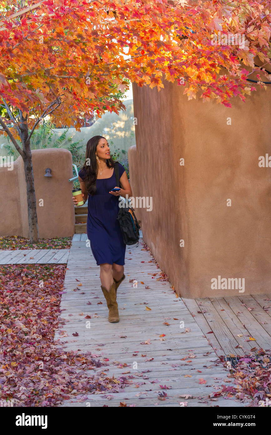 Hispanic woman carrying coffee and text messaging on cell phone Stock ...