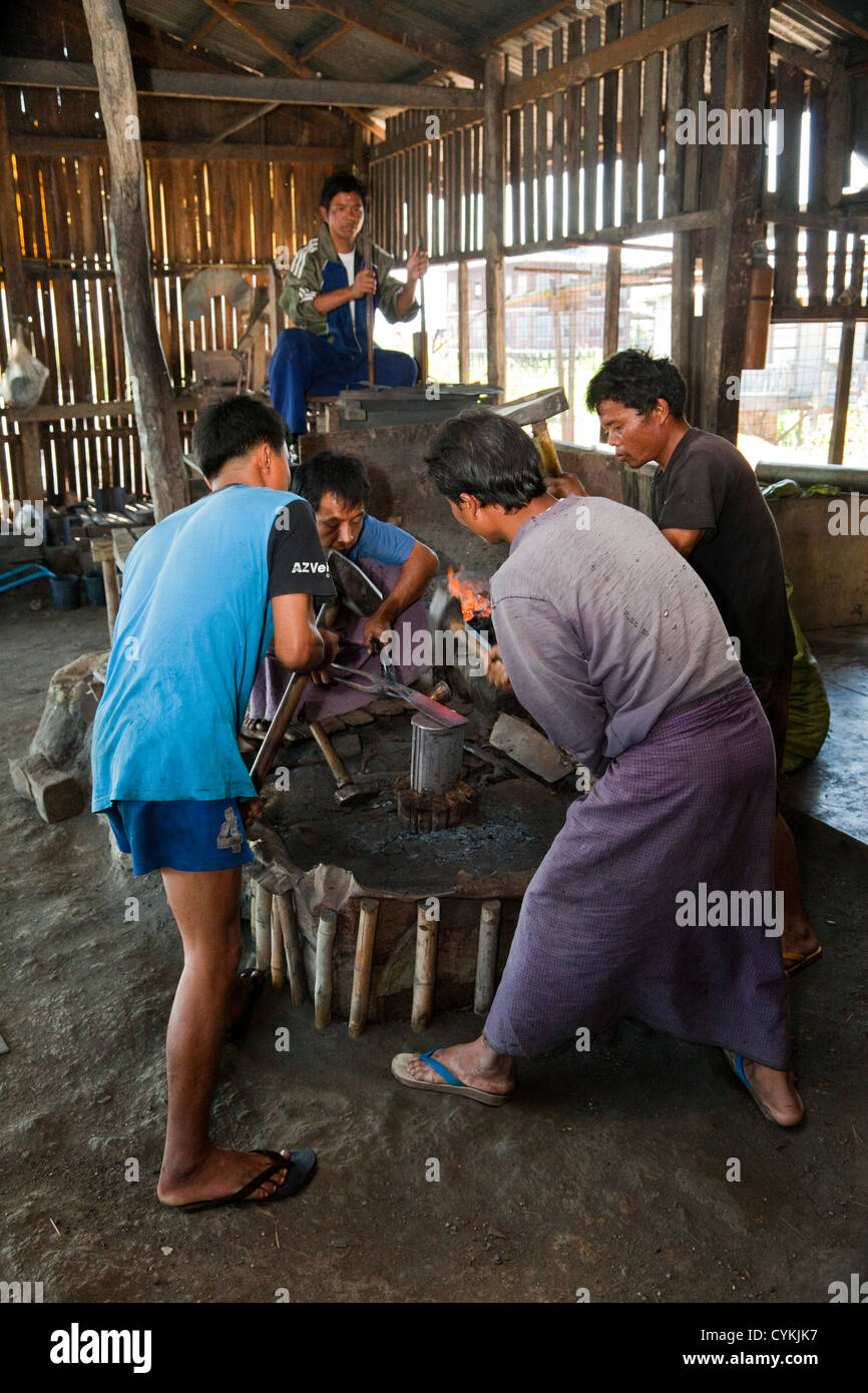 Myanmar, Burma. Three Young Men Hammer Red-hot Metal Just Taken from the Blacksmith's Fire, Inle Lake, Shan State. Stock Photo