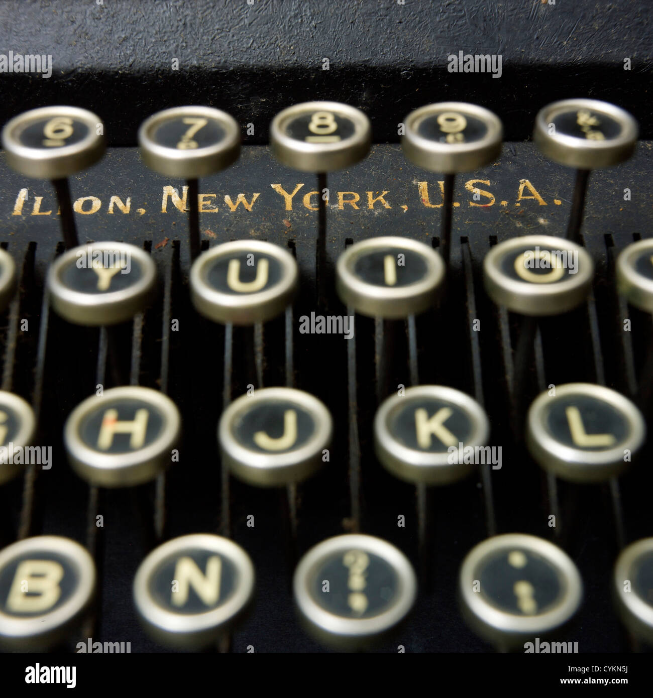 Small typewriter with keyboard in focus over a page of a book. Decoration  item. Concepts of reading, writing, old times, past. Close up. Blurred  background. Stock Photo