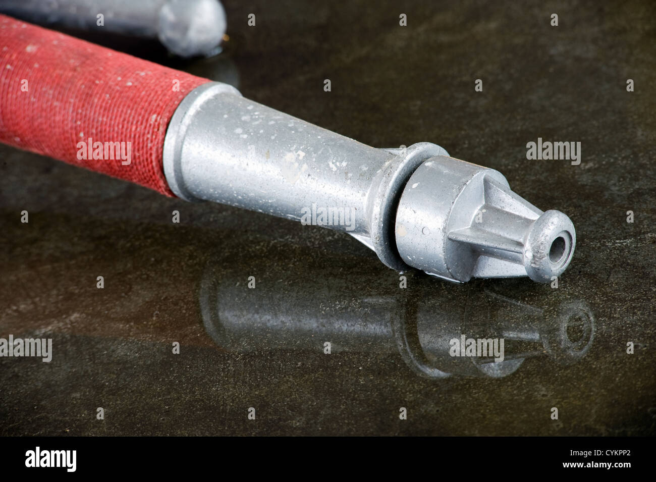 A nozzle on the wet floor in a firestation used by firefighters Stock Photo
