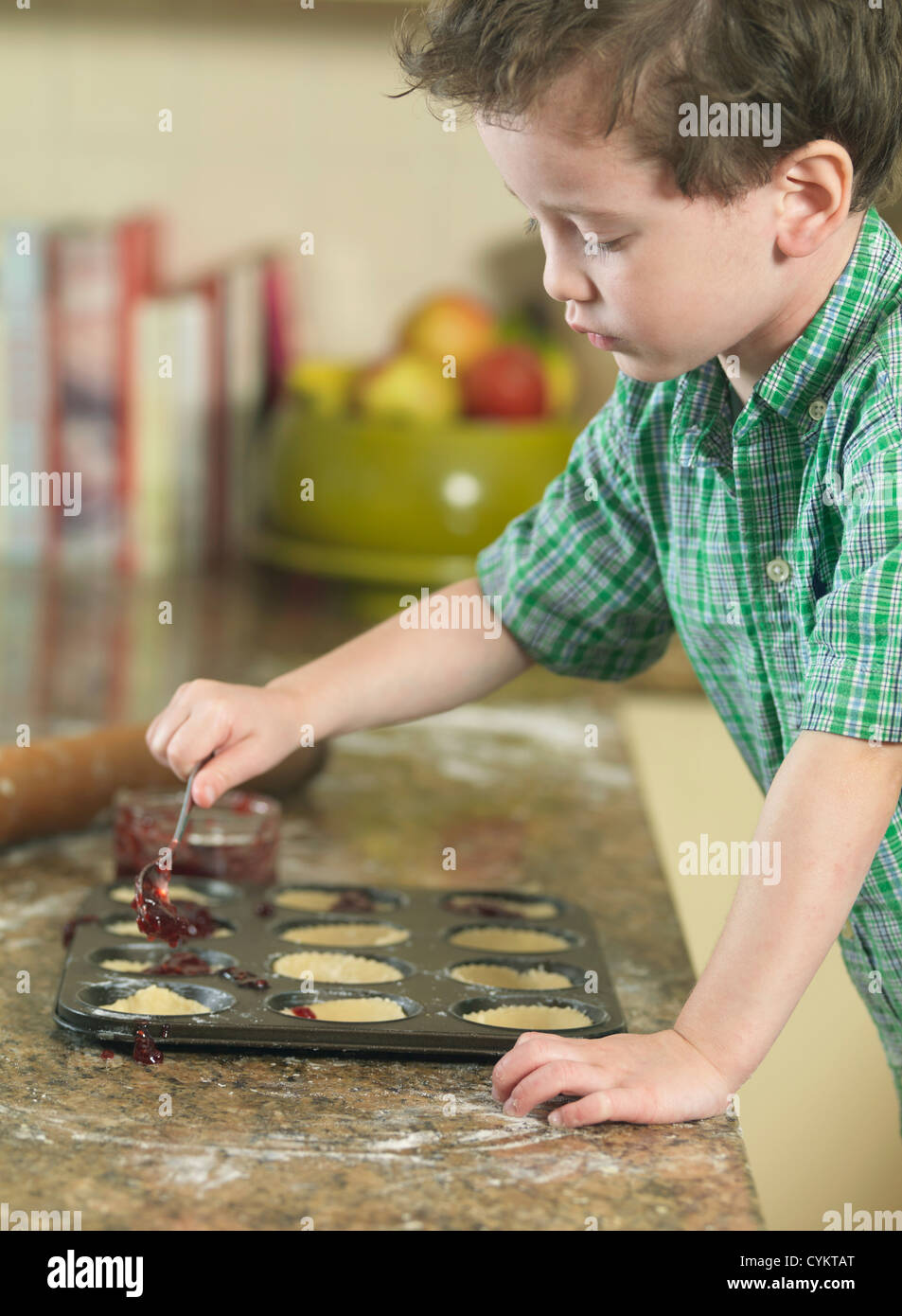 Boy spooning batter into pan in kitchen Stock Photo