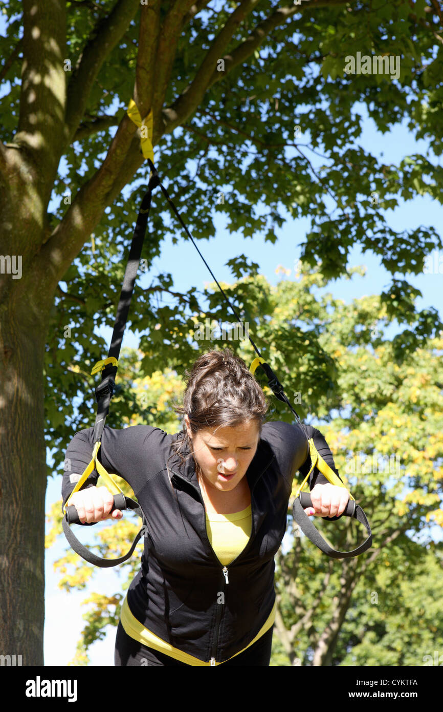 Woman using exercise straps outdoors Stock Photo
