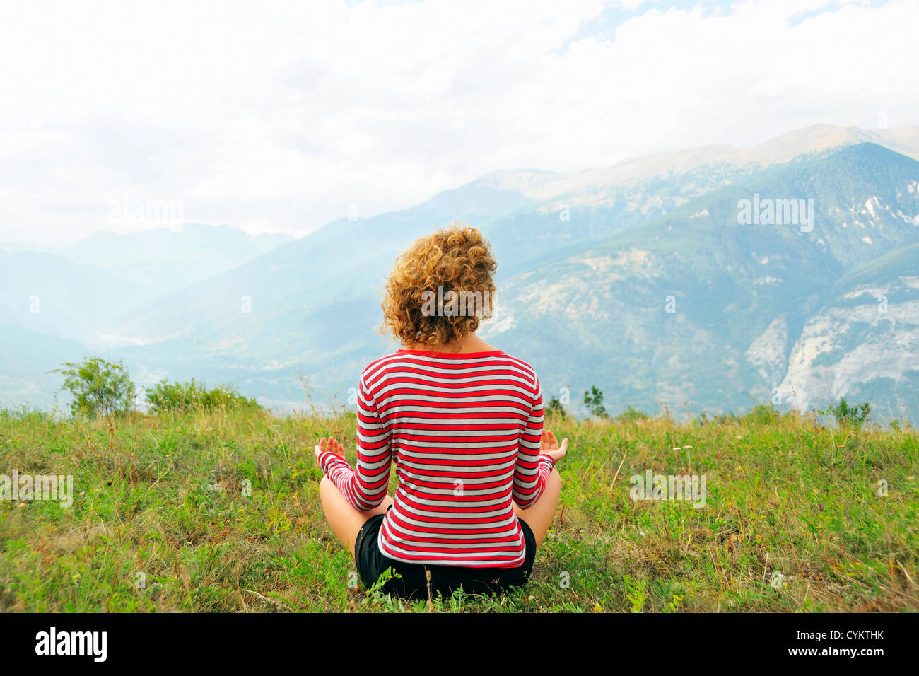 Woman meditating on rural hilltop Stock Photo