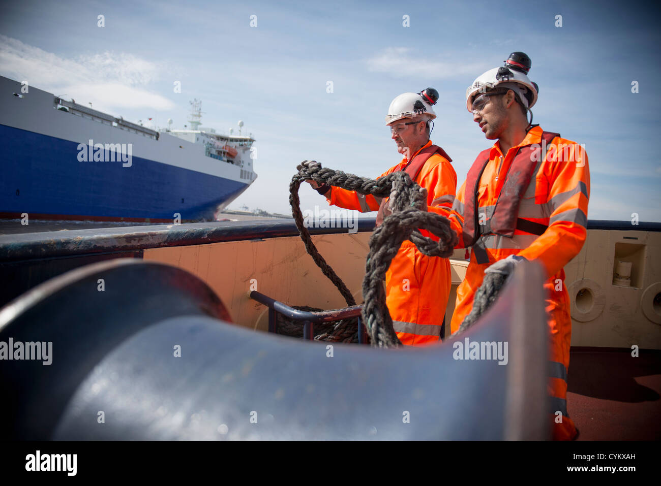 Workers on tug boat holding rope Stock Photo