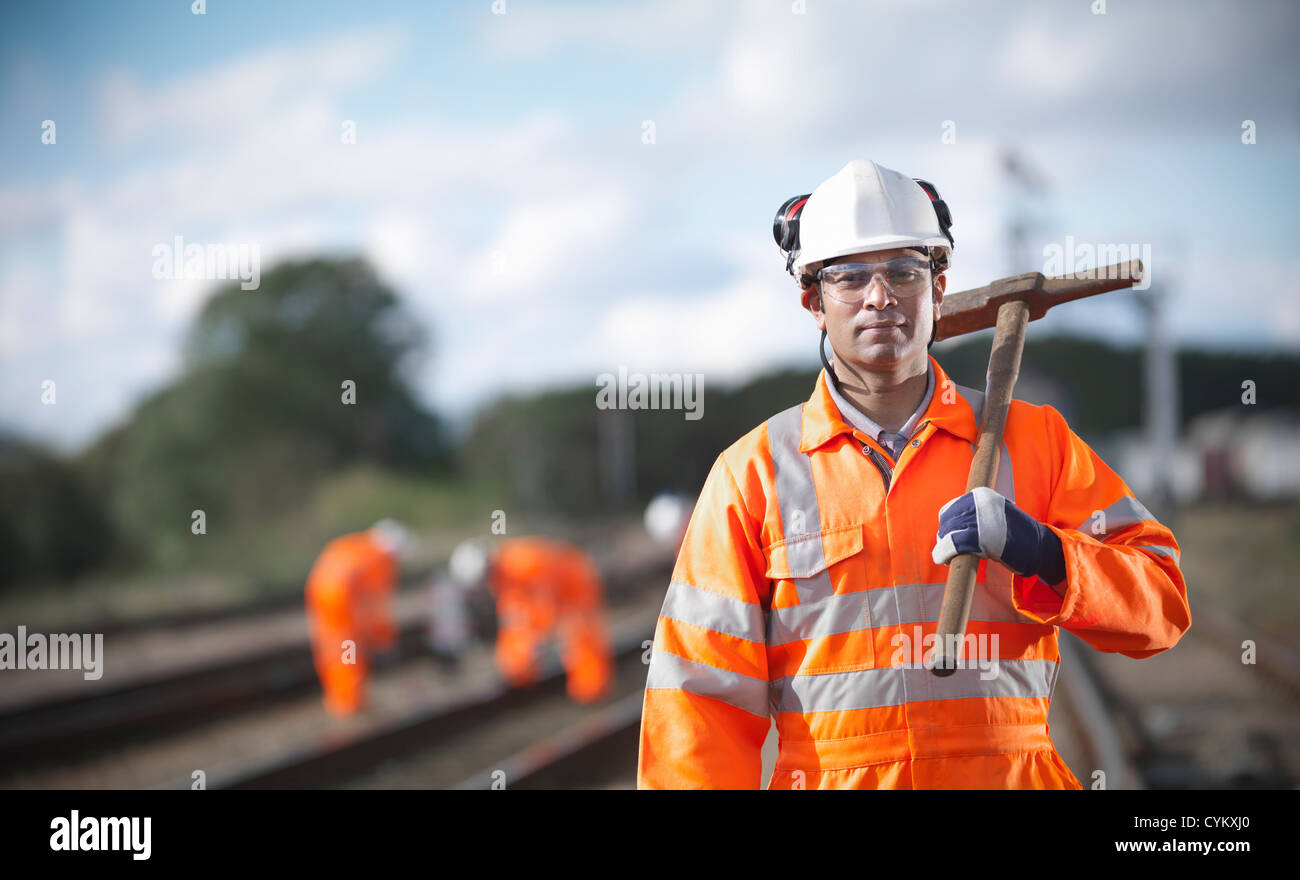 Railway worker carrying sledgehammer Stock Photo