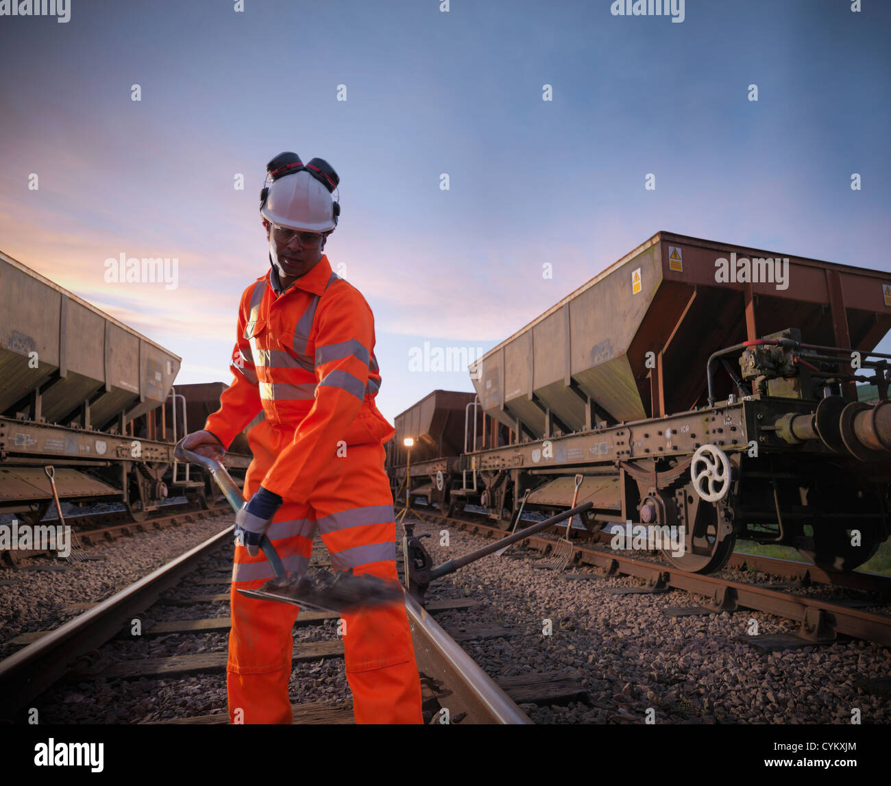 Railway worker shoveling on train tracks Stock Photo