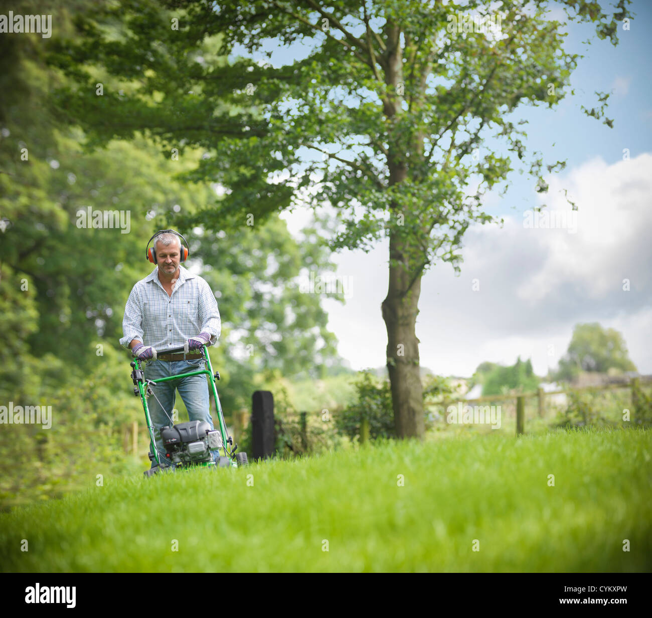 Man wearing headphones and mowing lawn Stock Photo Alamy