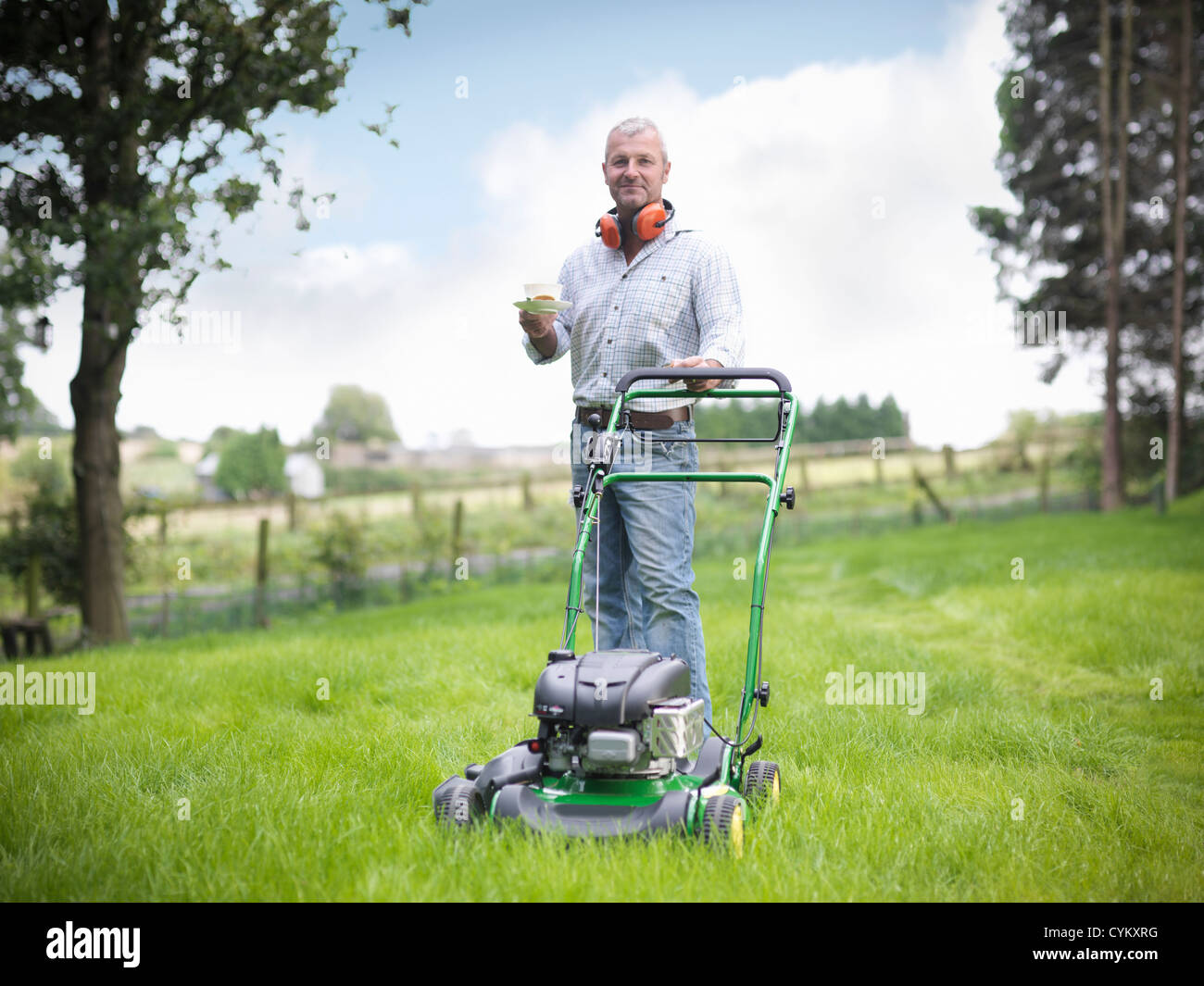 Man with lawn mower having cup of tea Stock Photo