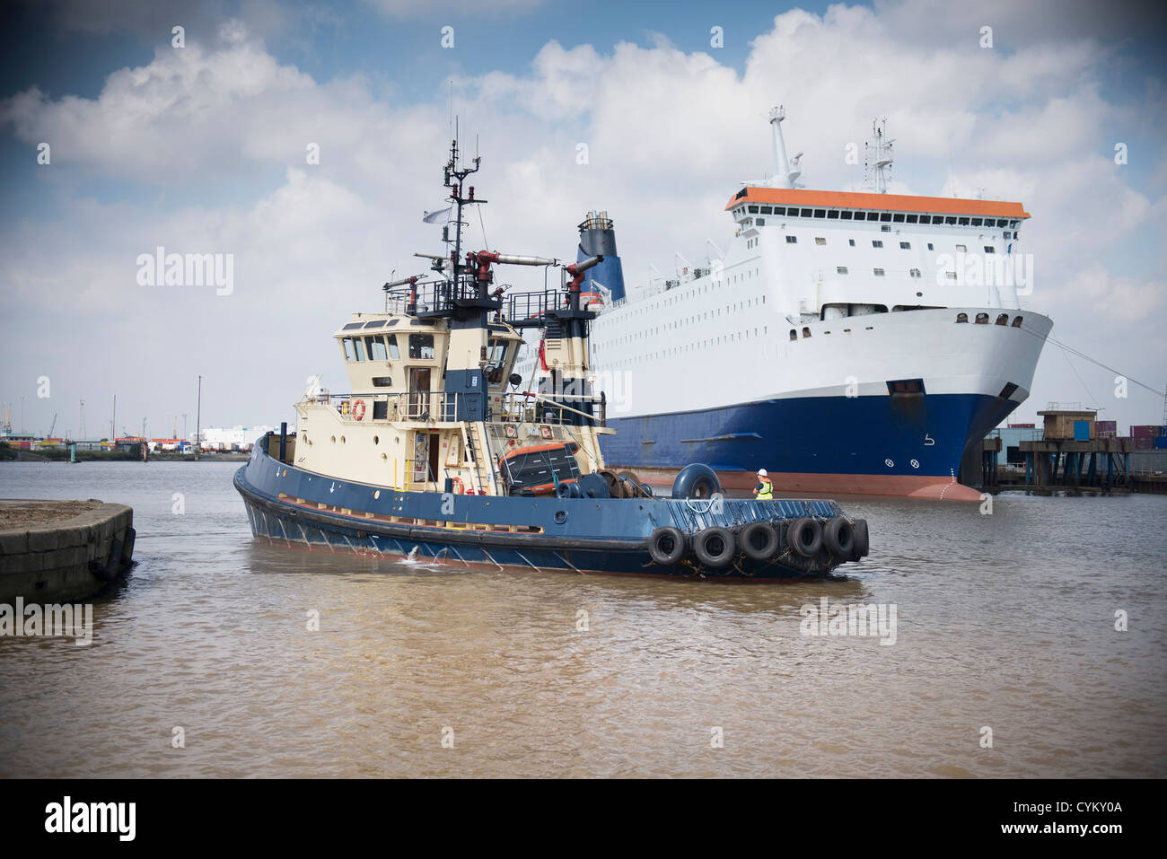 Tugboat sailing in urban harbor Stock Photo