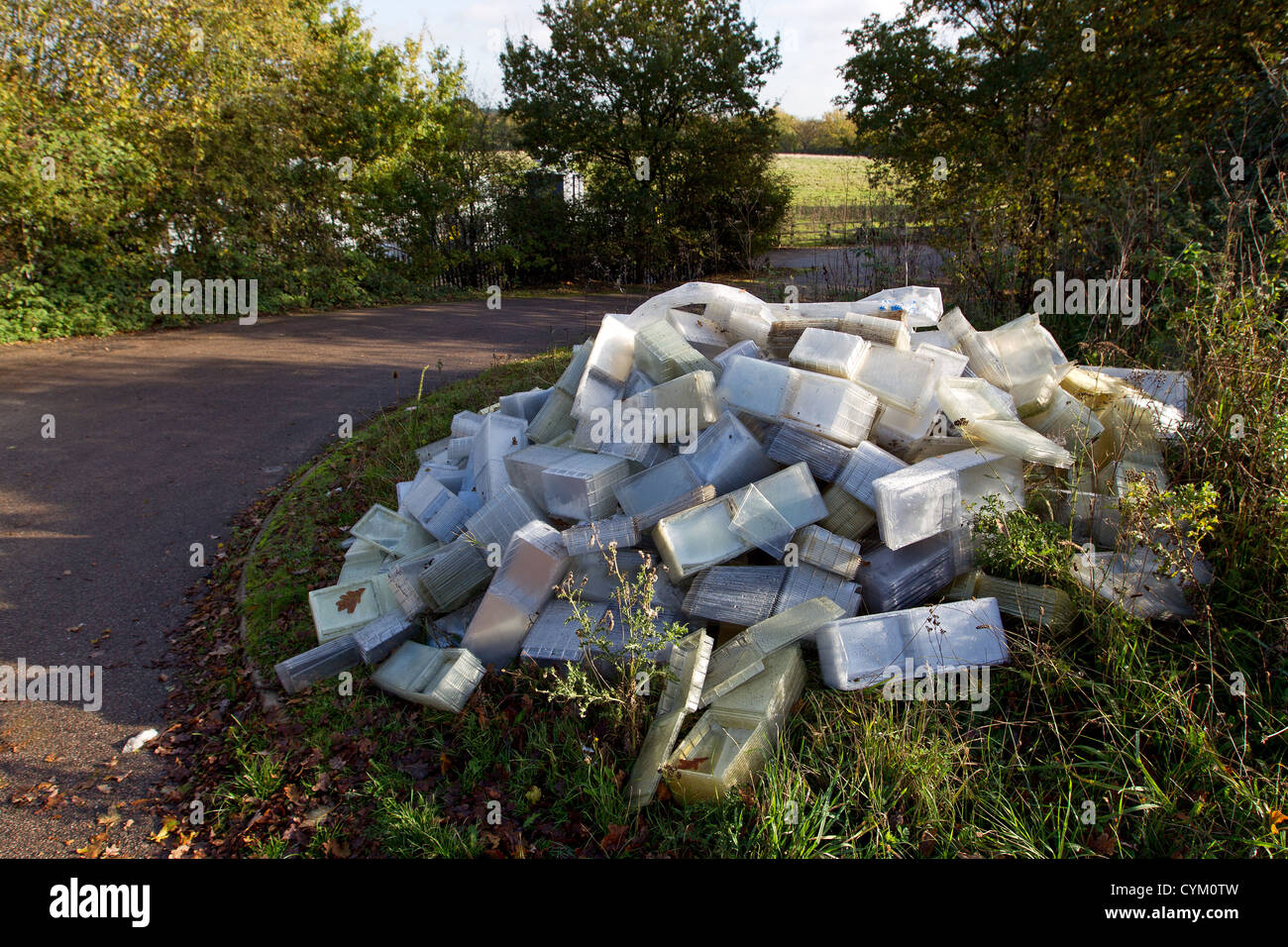 Plastic containers fly tipped in a country lane in the UK Stock Photo