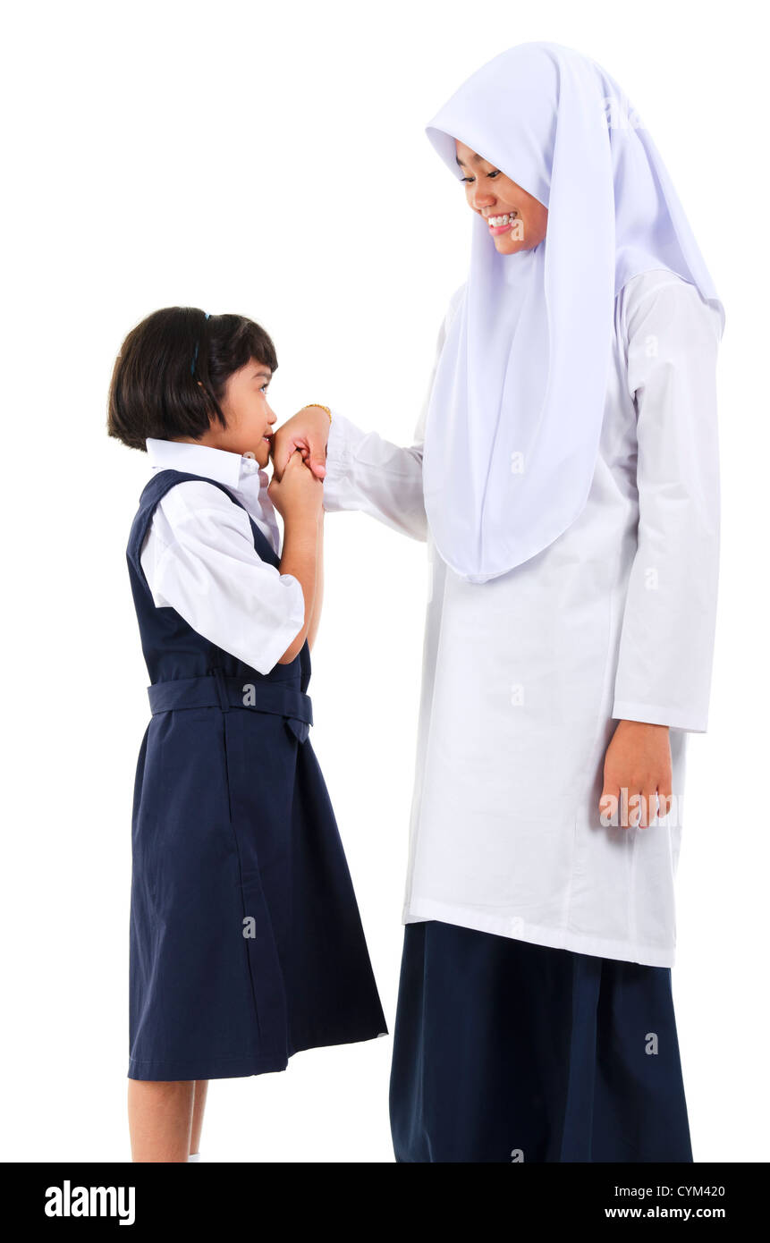 Young Southeast Asian Muslim girl  greeting to her elder sister over white background Stock Photo