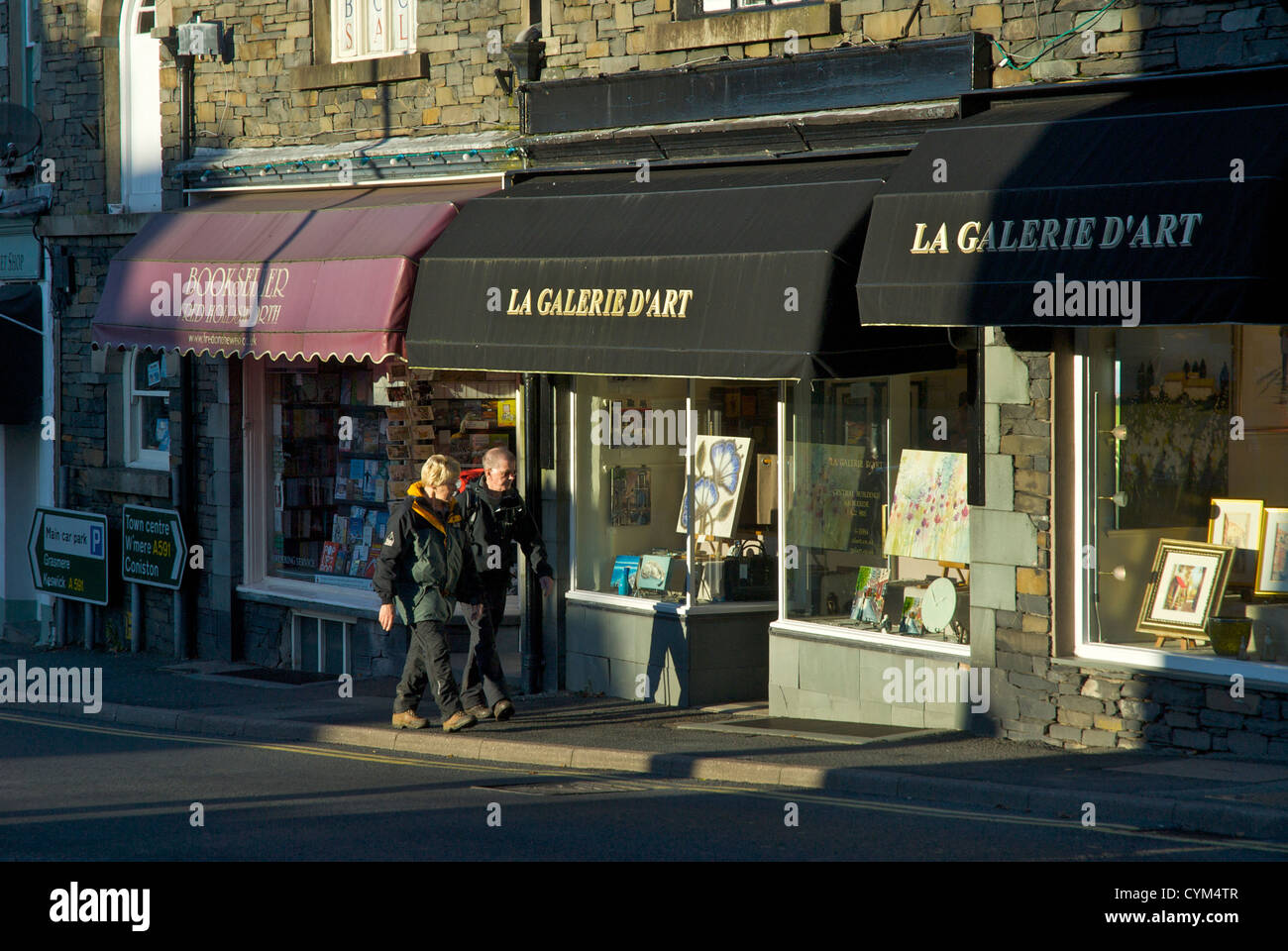 Two people walking past shops in Ambleside, Lake District National Park