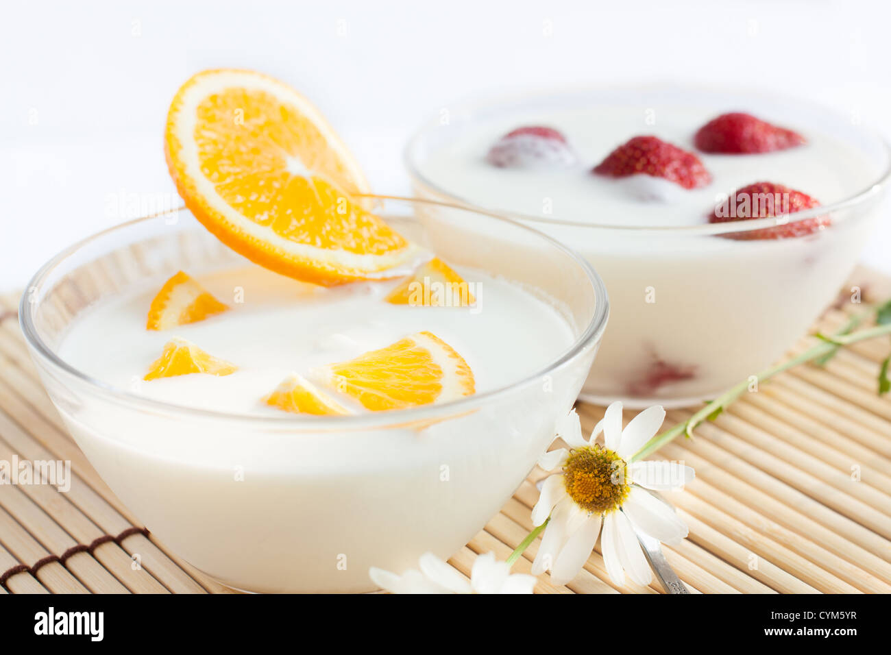 Strawberry yogurt and orange in transparent bowls Stock Photo