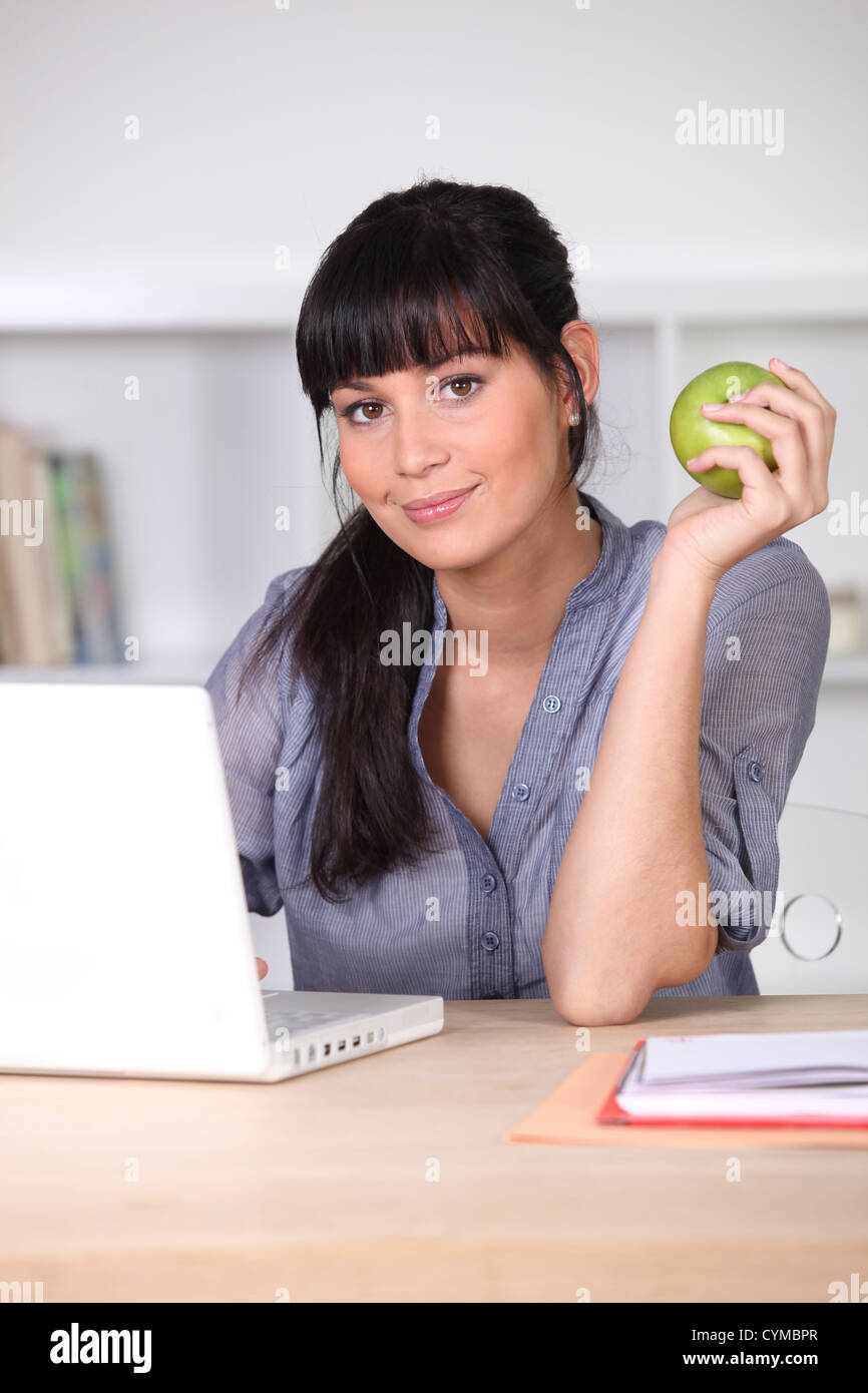 Woman with an apple sitting at her laptop Stock Photo - Alamy