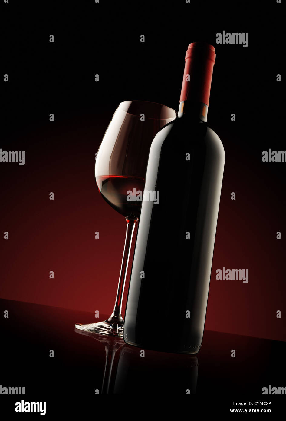red wine bottle and wine glass , red light on background Stock Photo