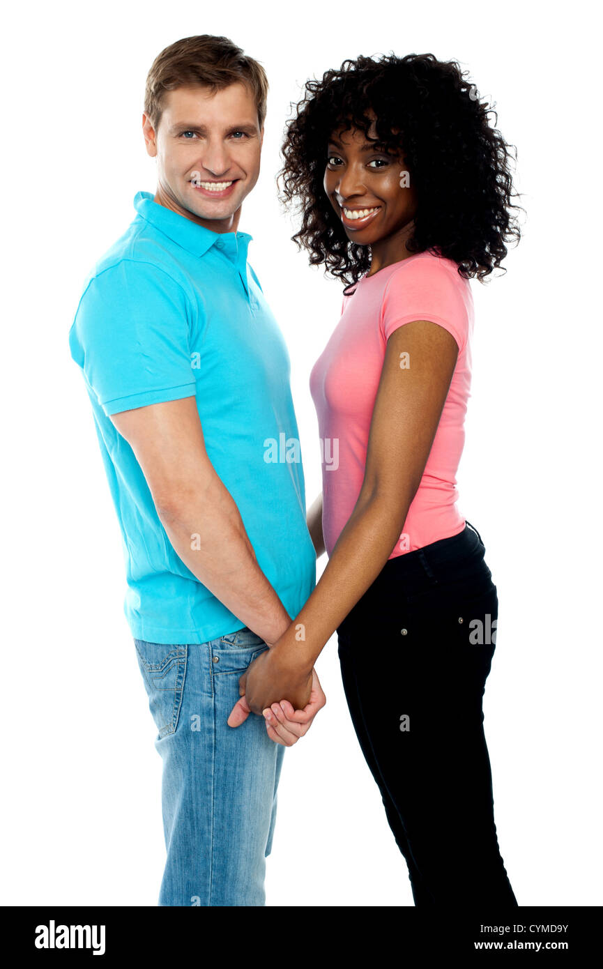 Happy young couple holding hands looking at camera Stock Photo - Alamy