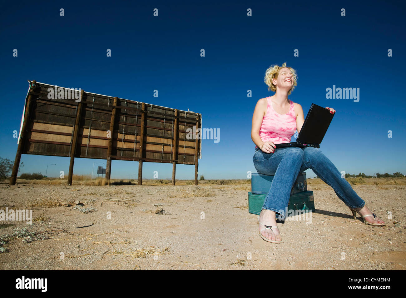 Woman with a laptop computer outside in front of an old bilboard. Stock Photo