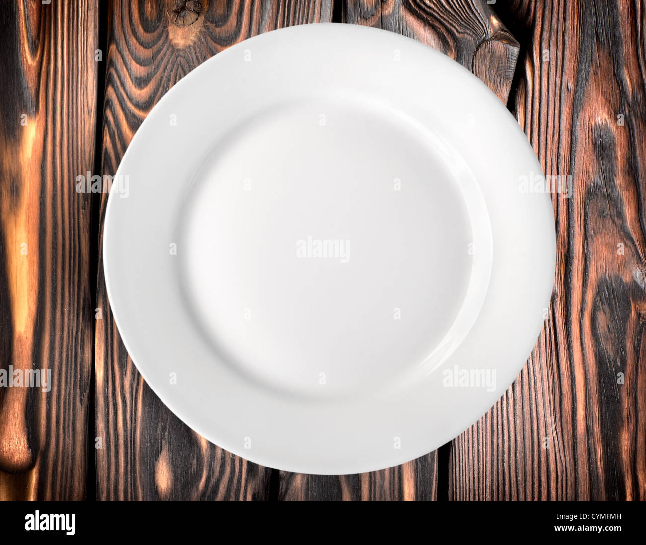 White plate on a dark wooden table Stock Photo
