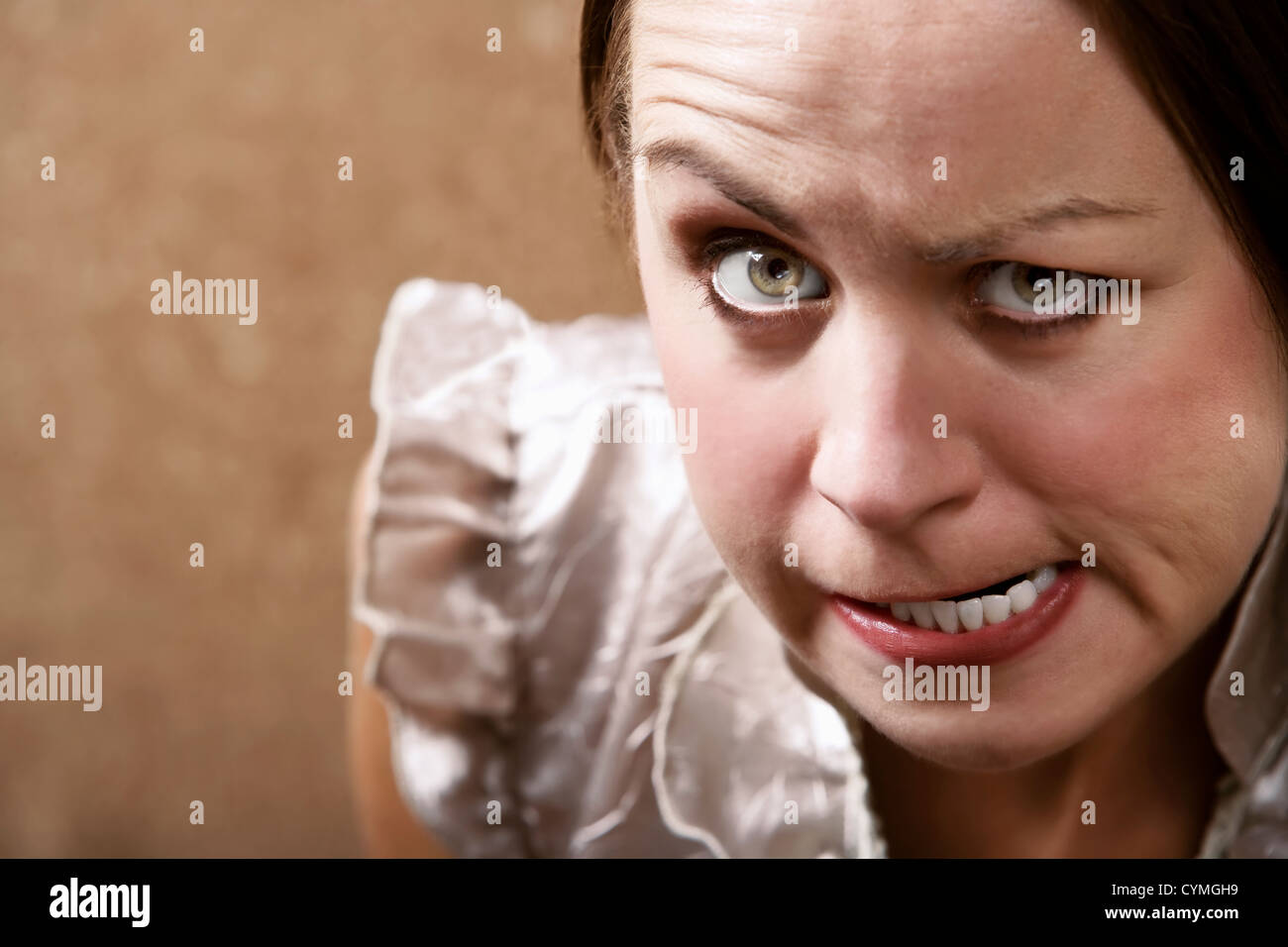 Young woman making stern face in front of a gold wallpaper background