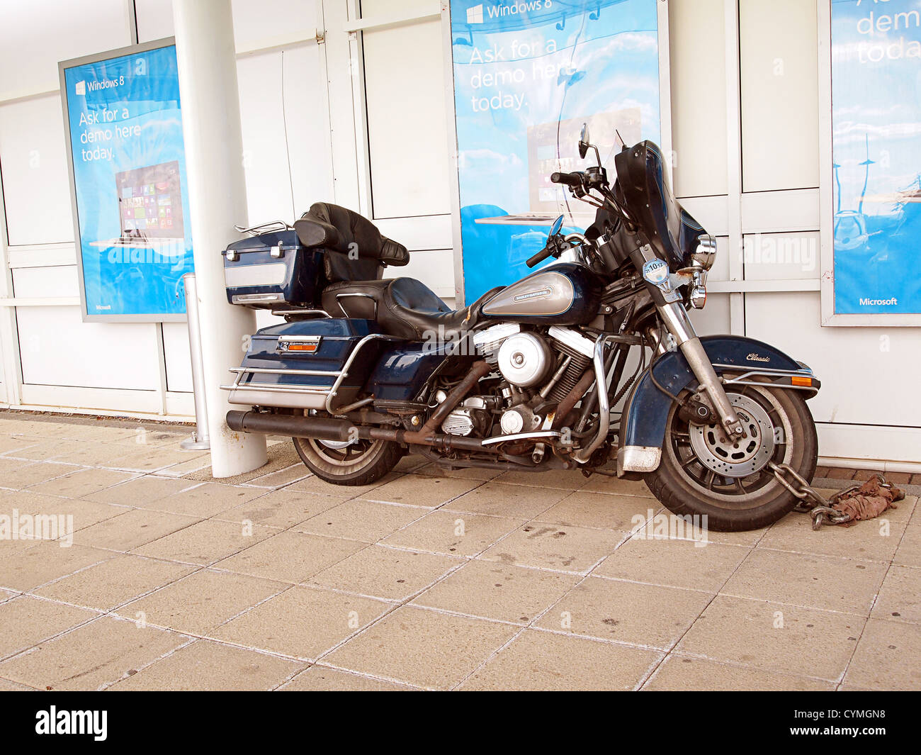 Well used Harley Davidson motor bike parked out side a retail store Stock Photo