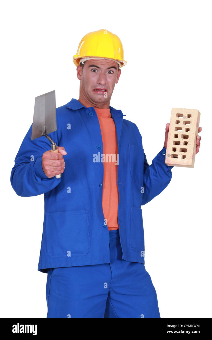 mason holding a trowel and a brick and looking disgusted Stock Photo