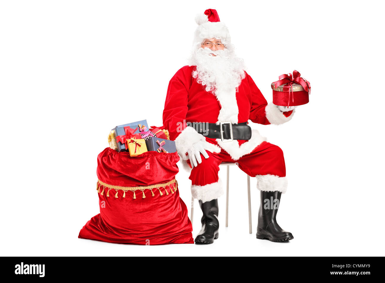 Santa Claus with a gift sitting next to a bag full of presents isolated ...