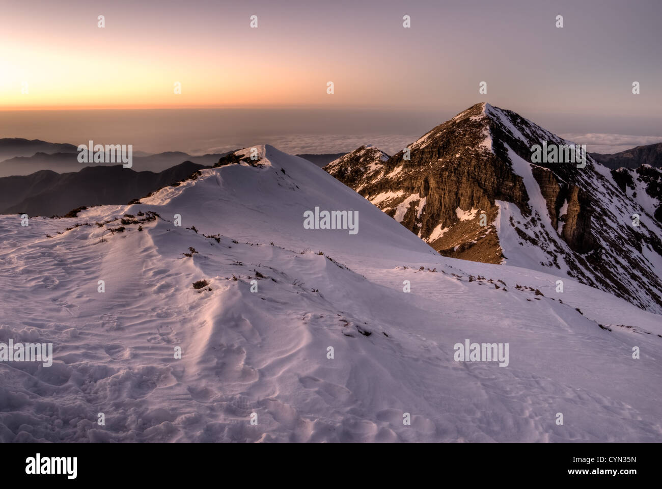 Mountain scenery with snow slop and dramatic peak in dusk sunset evening. Stock Photo