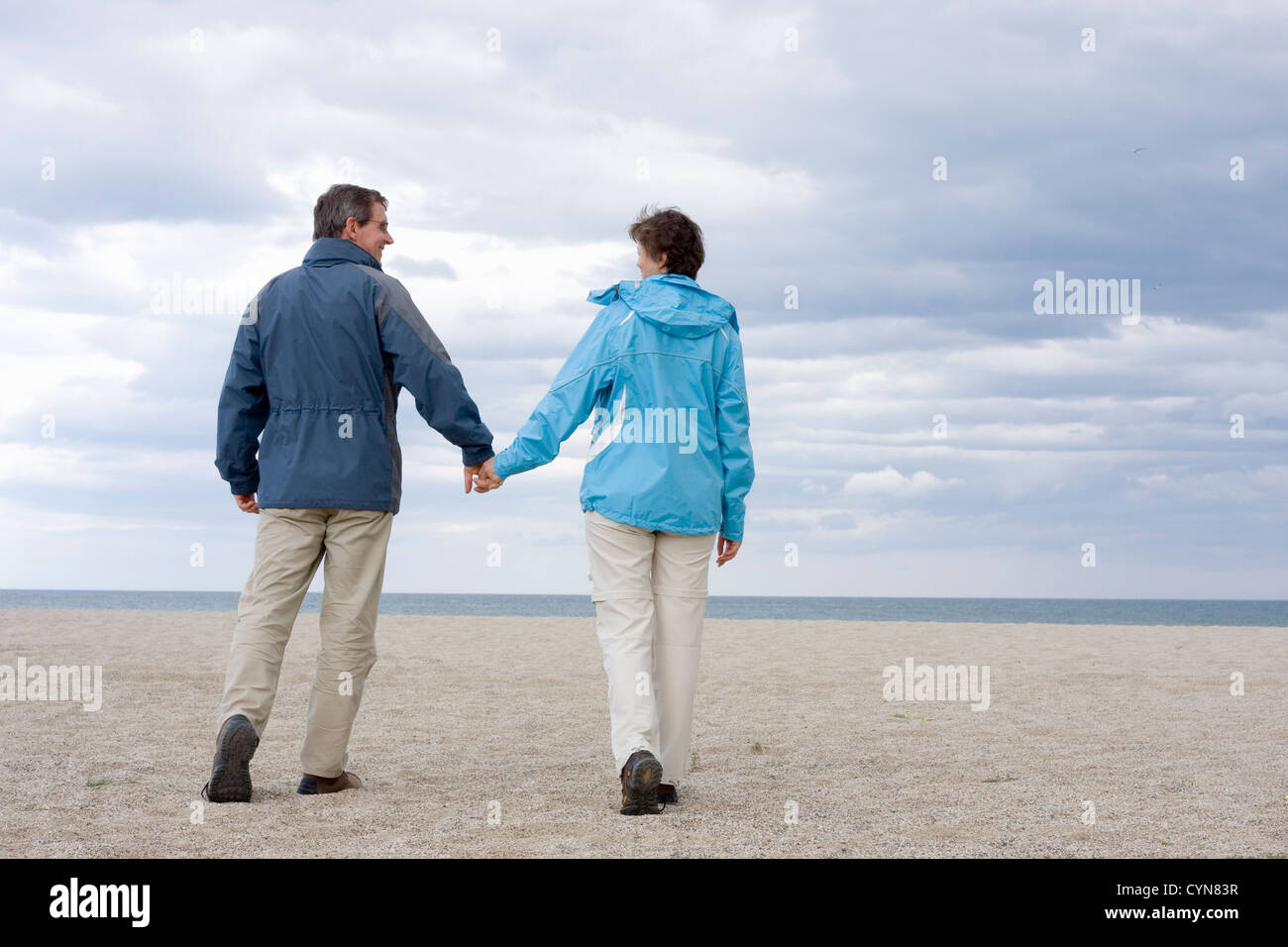 Mid-adult couple walking hand in hand on the beach Stock Photo - Alamy