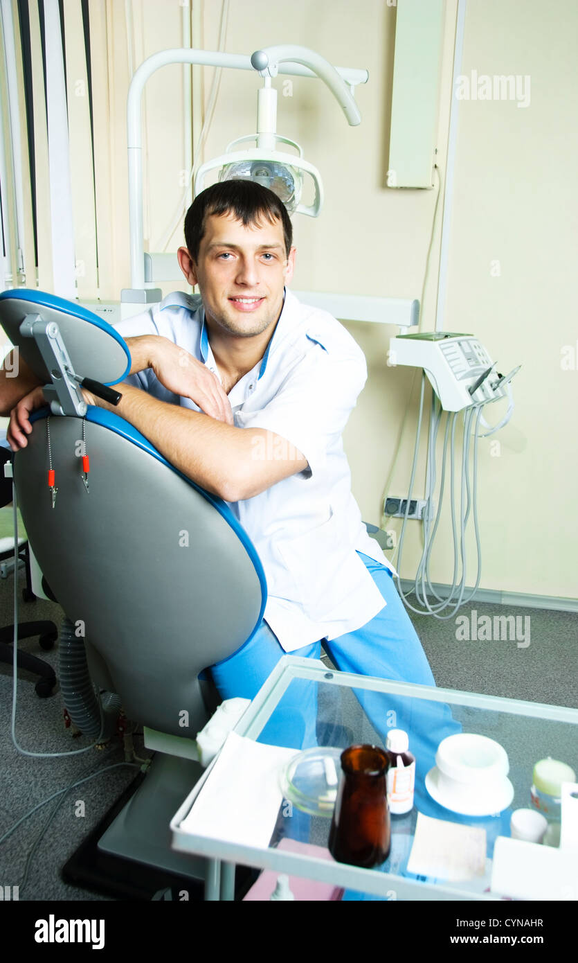 portrait of a young dentist sitting on the chair in his office Stock ...