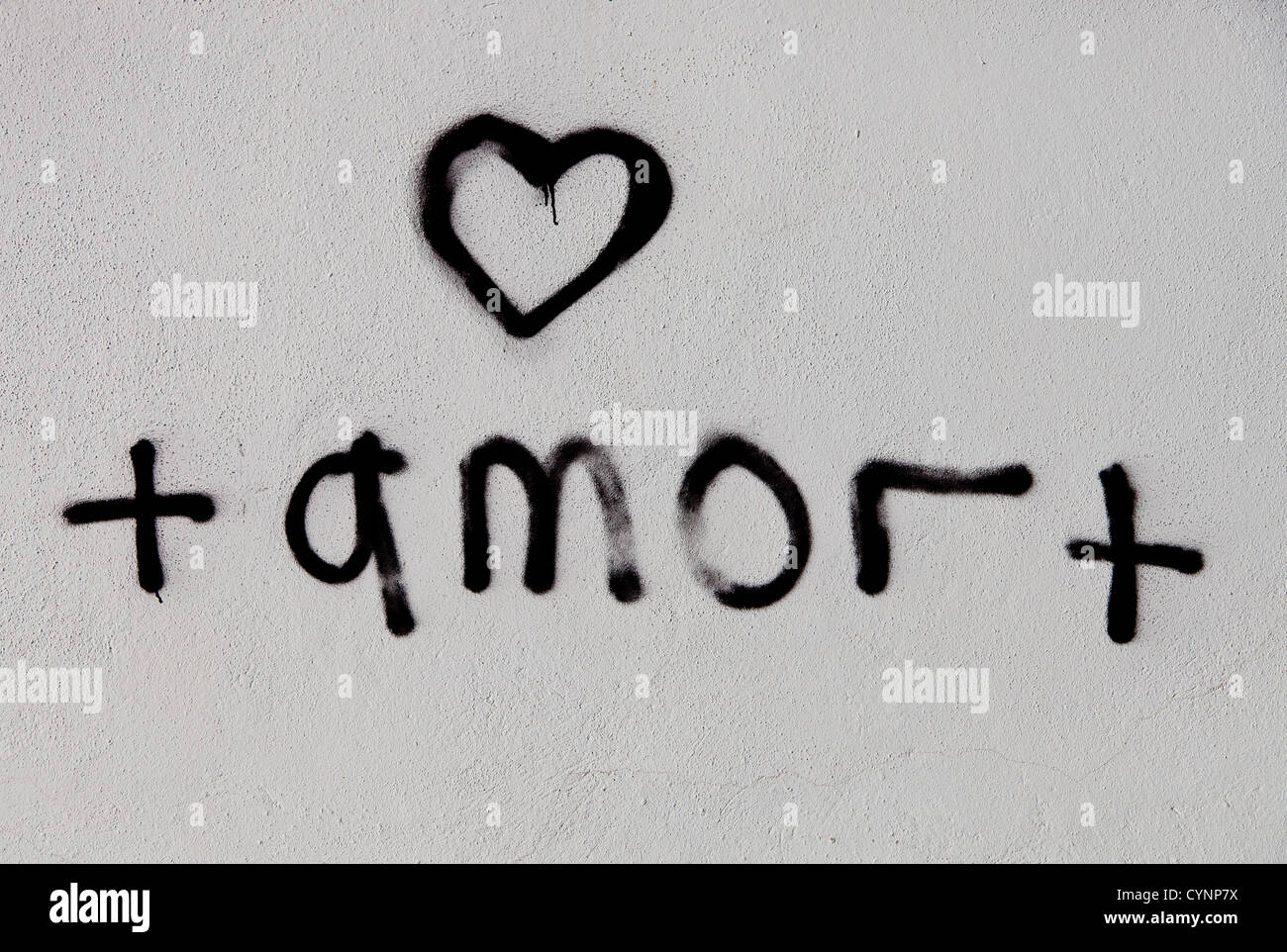Portuguese graffiti stating 'amor' on a white washed wall in Albufeira. Latin word for love with a heart painted above Stock Photo