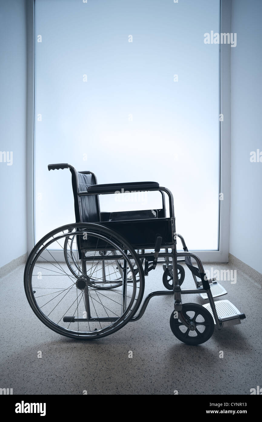 Empty wheelchair parked in hospital hallway Stock Photo