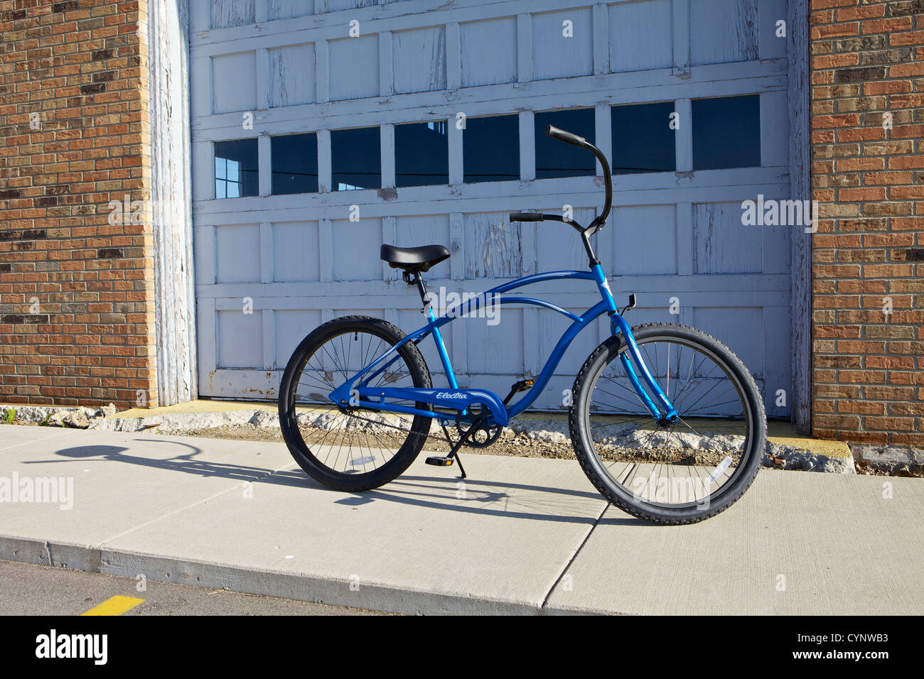 Blue Electra beach cruiser bicycle in front of a garage door on a