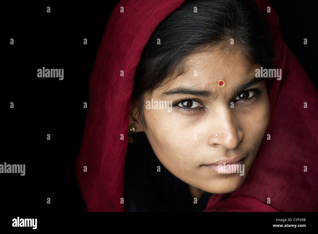 Indian girl wearing a red veil against a black background. Andhra Pradesh, India Stock Photo