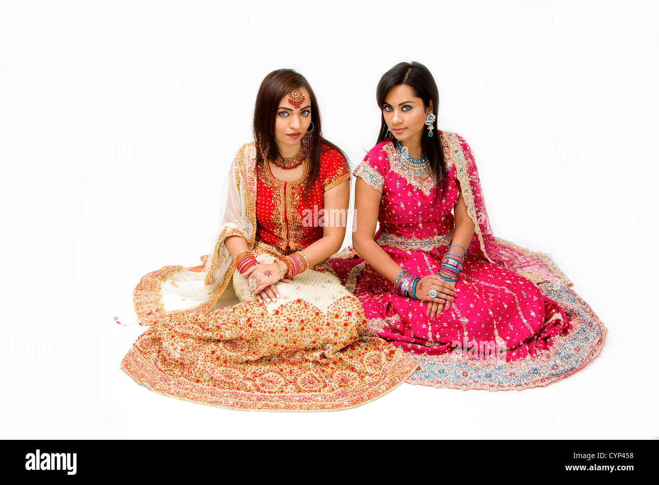 Two beautiful harem girls or belly dancers or Hindu brides sitting, isolated Stock Photo