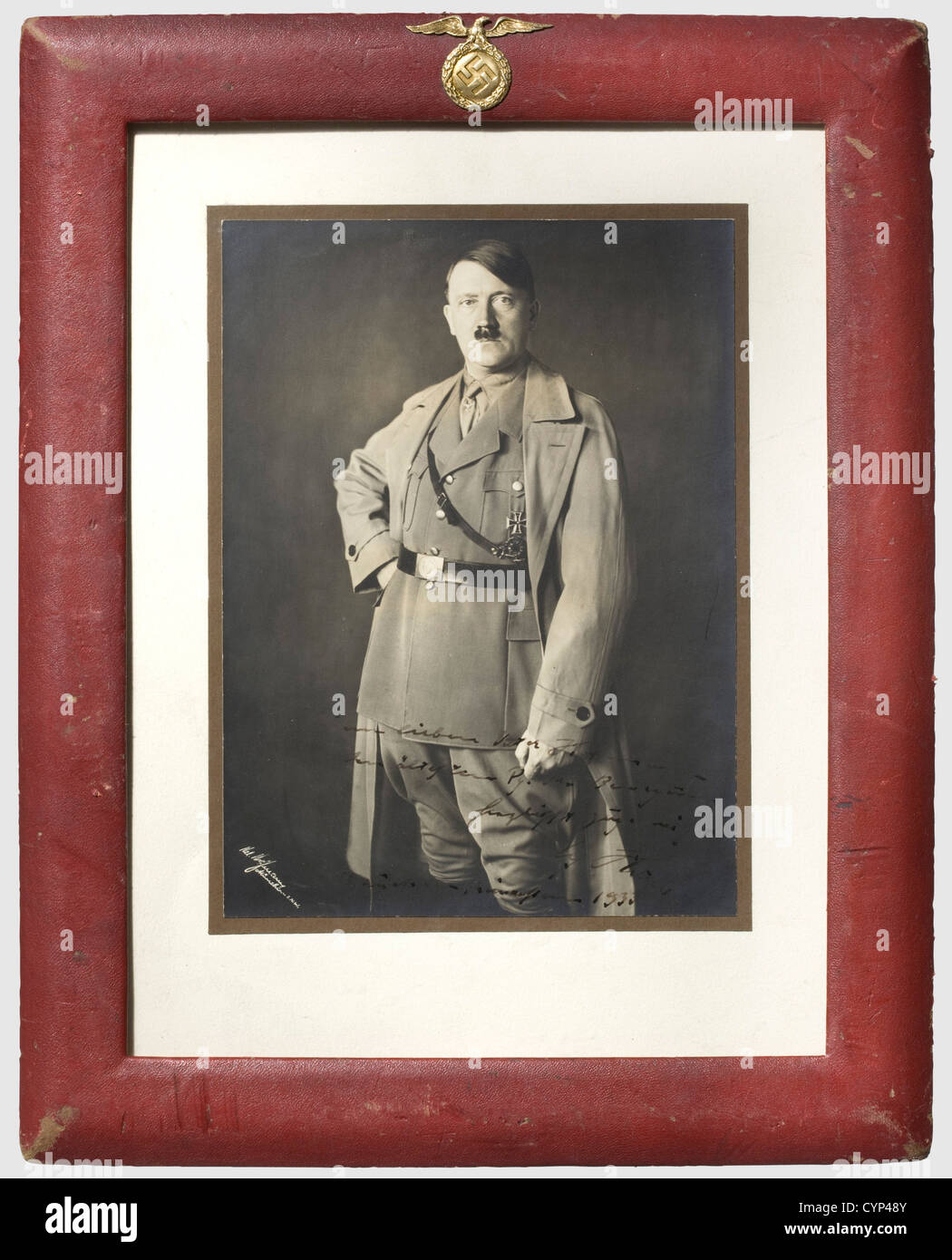 Adolf Hitler - Andreas Hofmann, A framed dedication photograph 'Dem lieben Vater Hofmann - dem Ältesten PG. der Bewegung herzlichst zugeeignet - Adolf Hitler - München, Weihnachten 1933' (For the dear Father Hofmann - the oldest party comrade of the movement kindest dedicated - Adolf Hitler - Munich, Christmas 1933). Photograph by H. Hoffmann, Hitler in his party uniform with coat. On passepartout, behind glass and in a ruby-coloured leather frame with a superimposed early-version national eagle made from brass on top. The reverse side also in ruby-coloured lea, Stock Photo