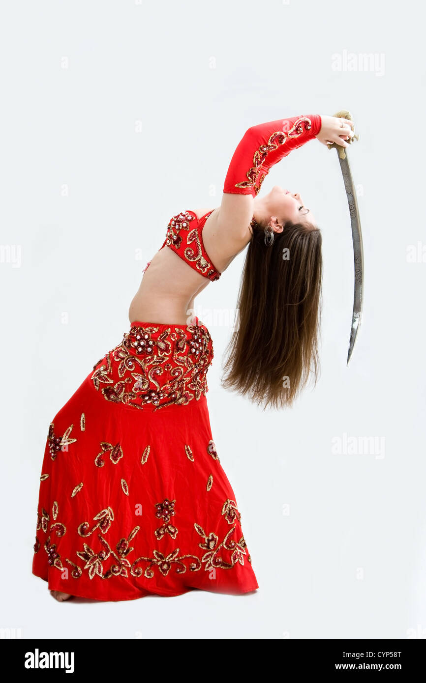 Beautiful belly dancer in red outfit holding sword hanging backward, isolated Stock Photo