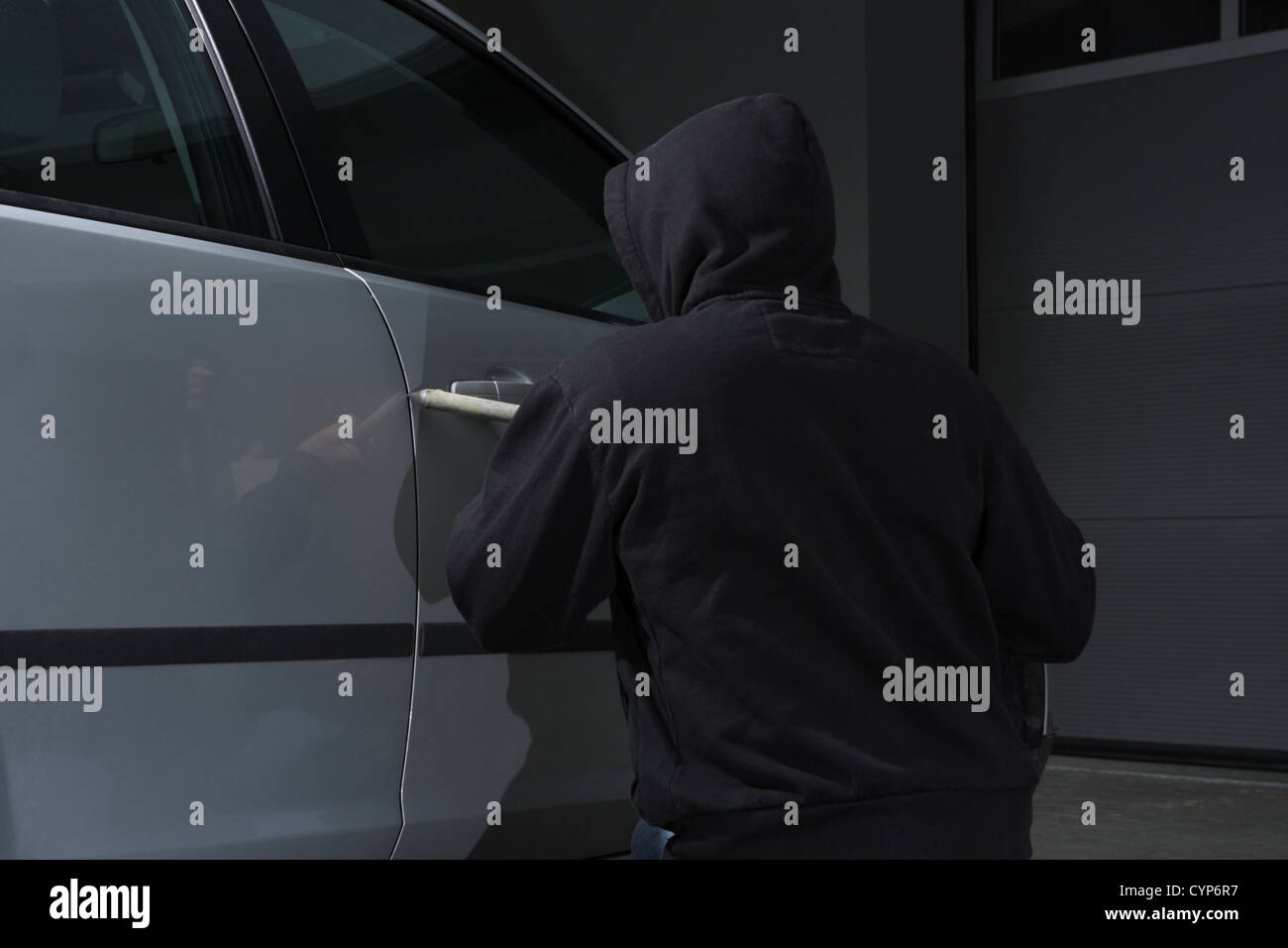 Thief burglar trying to break a car door Stock Photo