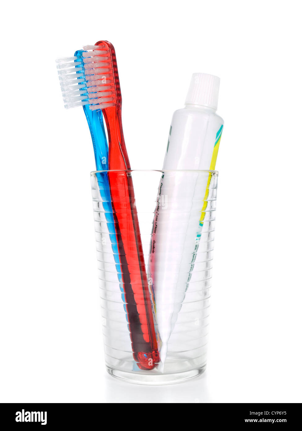 Two toothbrushes and a tube of toothpaste in a glass over white