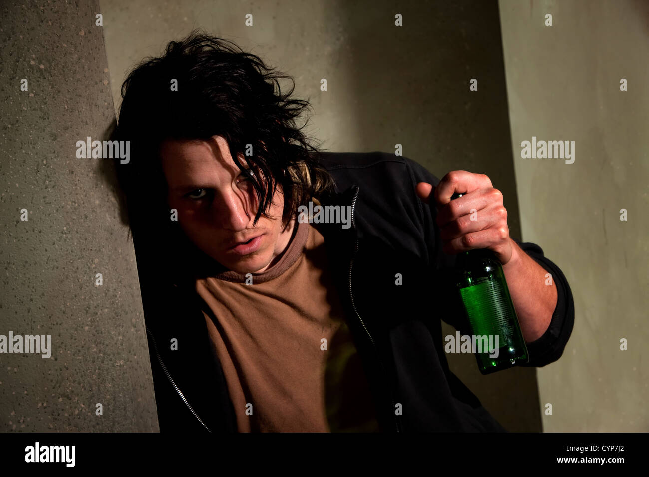 Drunk young man leaning on a wall with beer bottle Stock Photo - Alamy