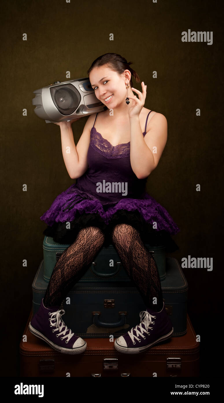 Pretty girl in funky purple outfit on green background with big radio Stock Photo