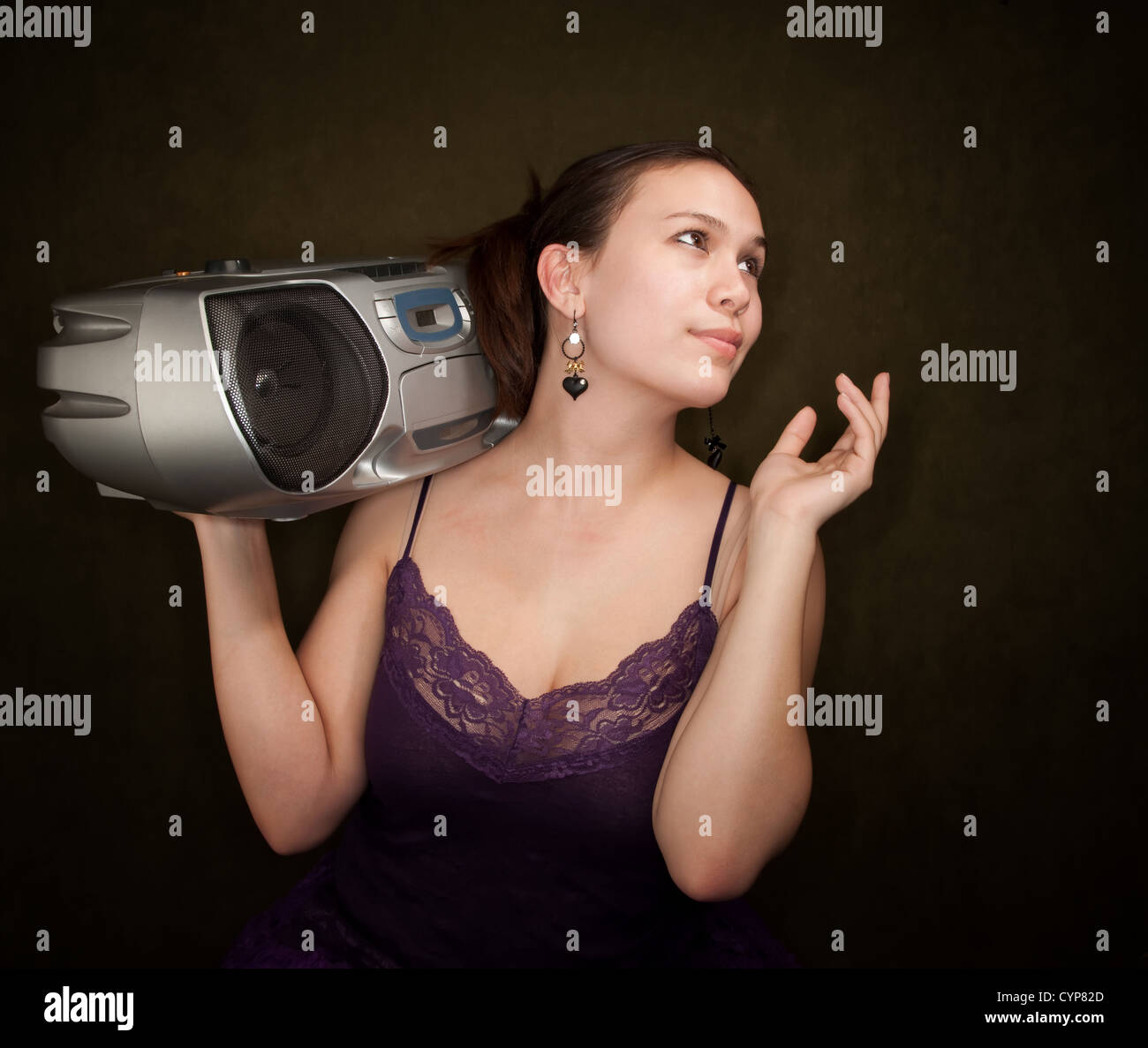Pretty girl in funky purple outfit on green background with big radio Stock Photo