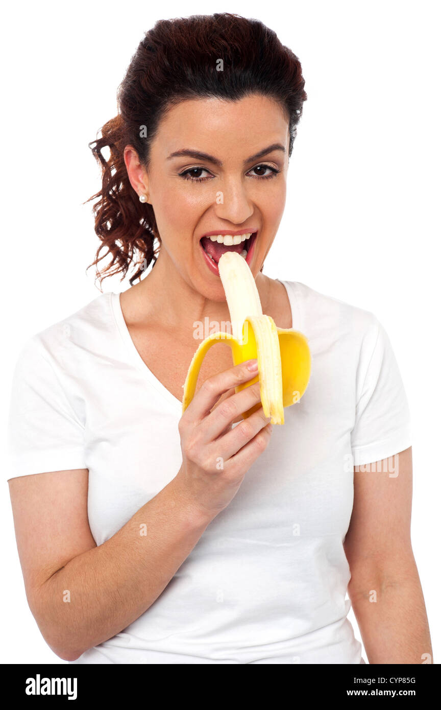 Beautiful young fit girl eating banana isolated on white background