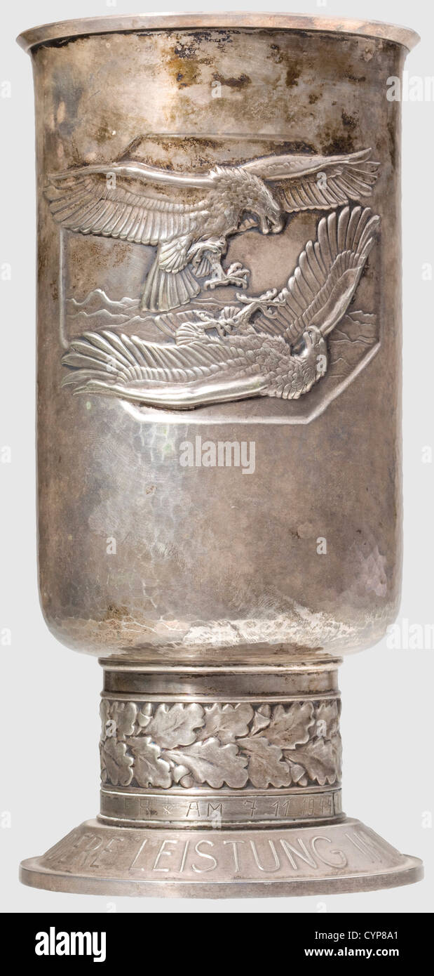 A Goblet of Honour for Outstanding Achievement in the Air War,the bottom punched 'Alpaka - Feinsilber - Auflage - Joh. Wagner & Sohn'. Above the original inscription ring a later inscription is applied,engraved 'Oberleutnant * Othmar Gratzer * am 7.11.1944'. Height 20.5 cm(Nie 7.08.02 2). Lightly toned,in very beautiful condition. The award to Othmar Gratzer is not verifiable. Included is a small tray made from the wood of a propeller,accompanied by eight schnapps beakers(dented)made from cartridges,historic,historical,1930s,20th century,Air Force,,Additional-Rights-Clearences-Not Available Stock Photo