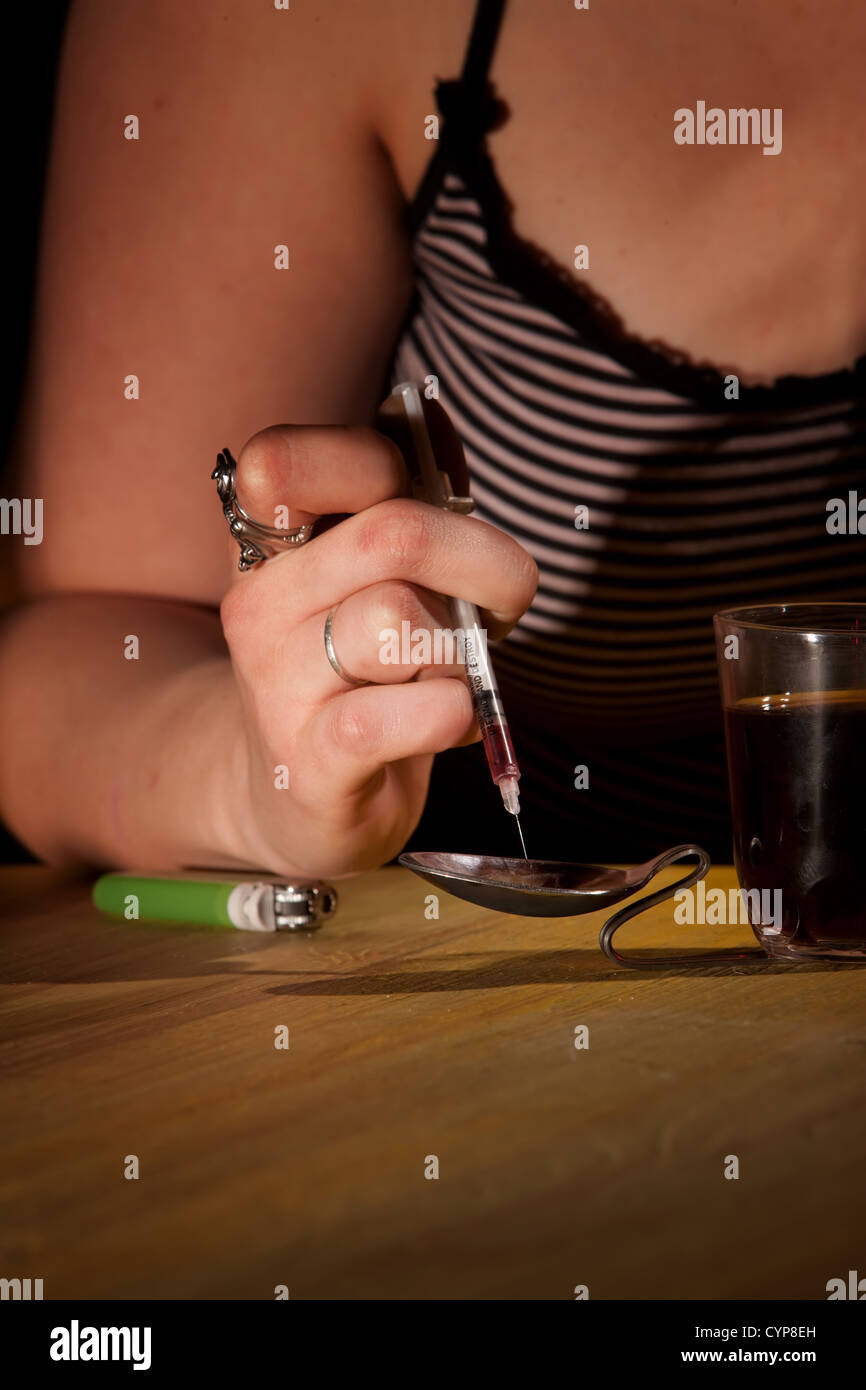 Closeup of woman's hand drawing black tar heroin into a needle Stock Photo