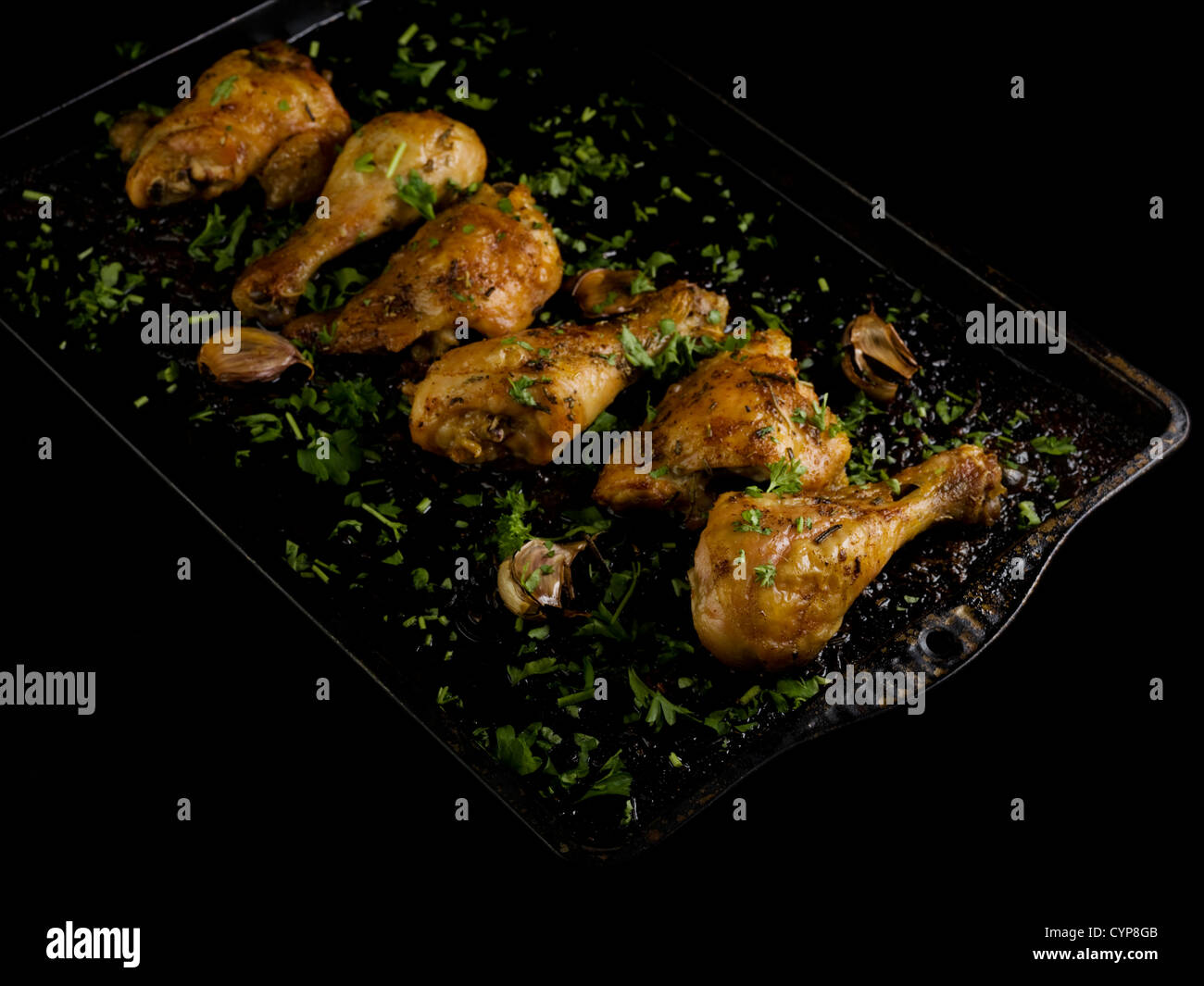 Oven grilled chicken drumsticks with garlic and herbs on tray Stock