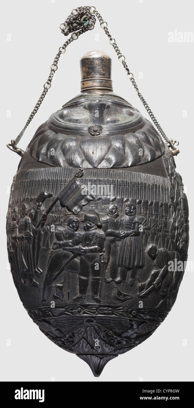 A colonial coconut bottle,circa 1800. The corpus continuously and lavishly carved in relief with depiction of Napoleon courted by his soldiers,on the reverse side scene of surrender with the handover of colours and sabre to Napoleon. At the bottom four eagles between floral frieze,the tip with medallion on one side surrounded by a bundle of trophies. Silver threaded spout and attached silver chain. Height 18 cm,historic,historical,people,19th century,France,Imperial,French Empire,object,objects,stills,clipping,cut out,cut-out,cut-outs,vessel,,Additional-Rights-Clearences-Not Available Stock Photo
